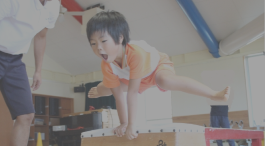 小さな子どもが跳び箱を飛んでいる写真