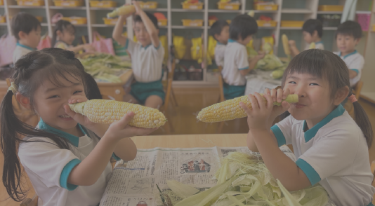 教室で子どもたちがとうもころしを持っている写真